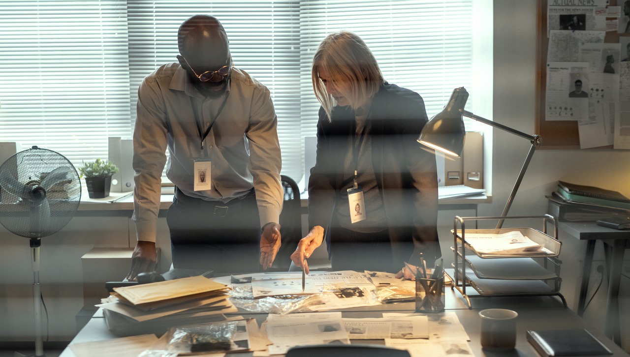 Two investigators looking at a folder of case notes on the table.